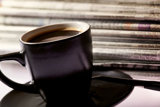 Cup of coffee and pile of newspapers on the table.