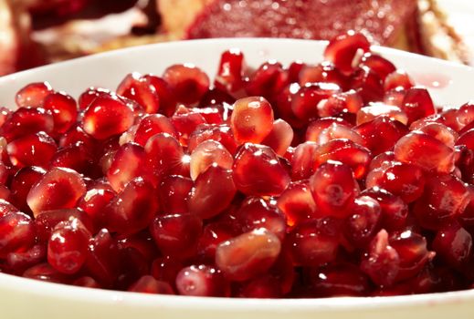 Pomegranate seeds in a white bowl.