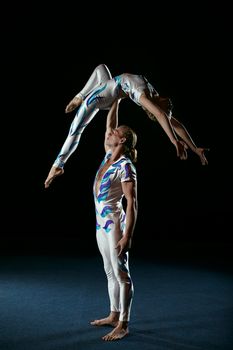 Circus artists perform different tricks. Man holding woman.