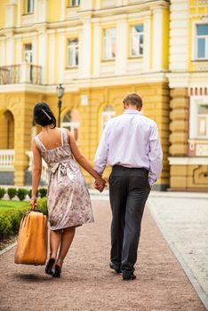 Couple walking away, woman with heavy case