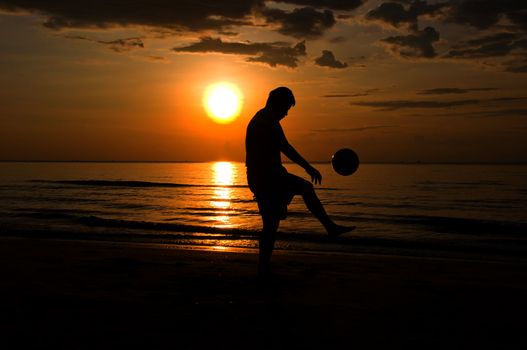 silhouette man playing soccer on the beach