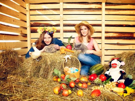 two girl with rabbit, cat and harvest on hayloft at summer day