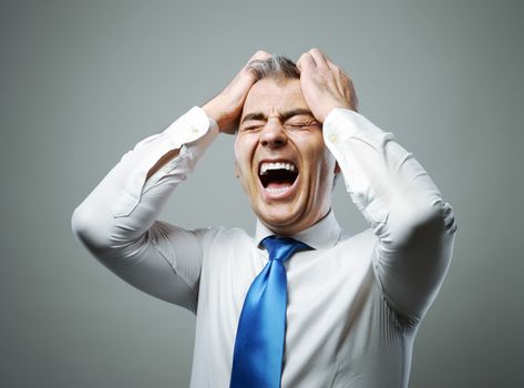 Frustrated mature businessman with his hands on his head while yelling