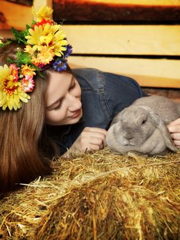 beautiful girl with rabbit on hayloft at summer day