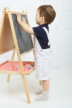 little boy drawing with chalk at blackboard