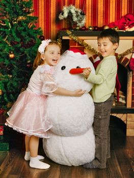two beautiful child and toy snowman near christmas tree