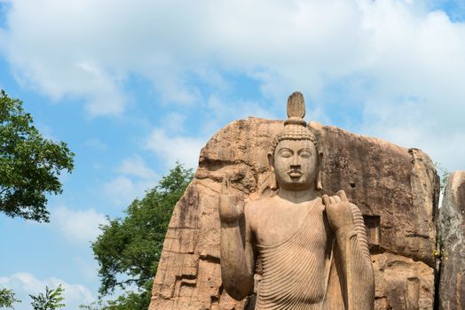 Avukana standing Buddha statue under blue sky, Sri Lanka. 40 feet (12 m) high, has been carved out of a large granite rock in the 5th century.