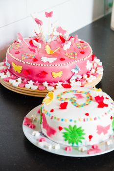 Delicious colorful decorated white and pink Marzipan cakes for a birthday party on kitchen dresser