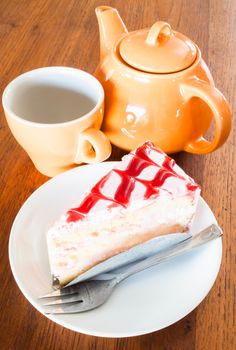 Tea break with white chocolate cake on wood table