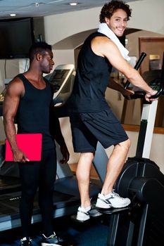 Young fit guy working out with trainer beside him