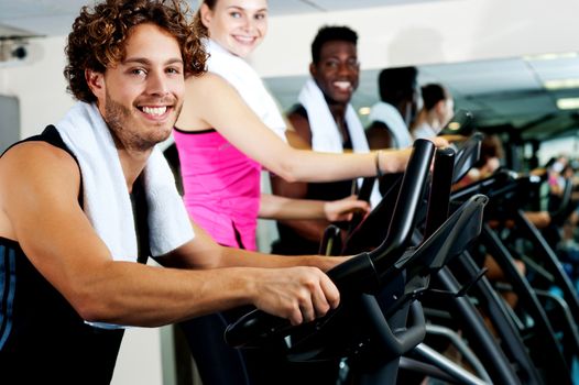 Smiling young people cycling at the fitness center