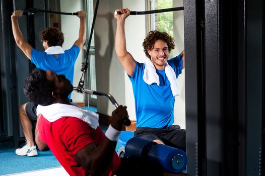 Confident young guys exercising in gym