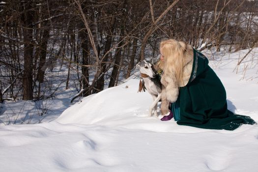 A blonde girl and a grey saluki on snow
