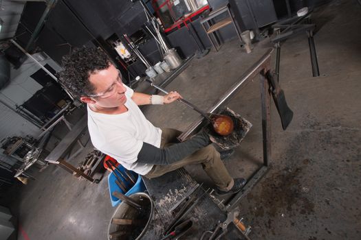 Handsome glass artisan handling glowing hot object