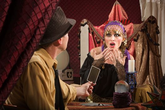 Frightened European female fortune teller looking at card