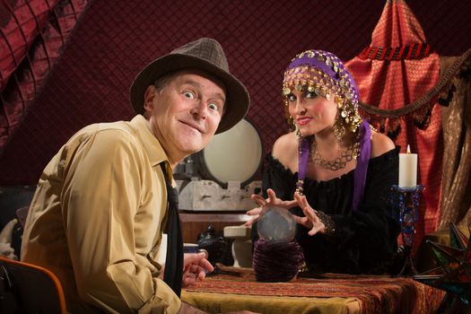 Excited Caucasian man with grinning crystal ball reading lady