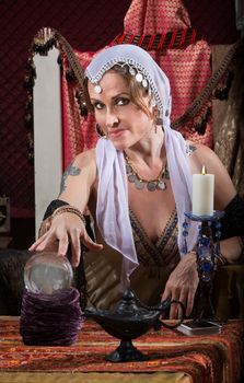 Exotic Romani woman with candle and crystal ball
