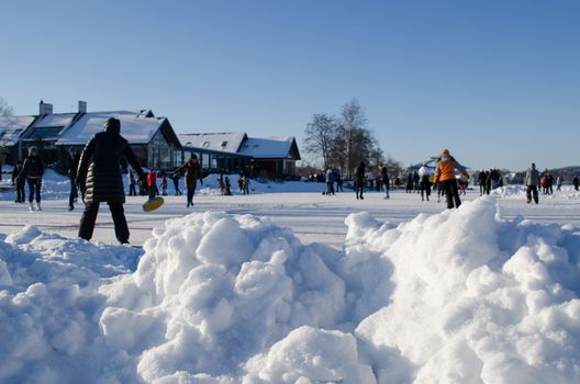 pile of snow closeup and active recreating leisure people in winter skating rink.