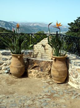 Place for a drink of water from mountain springs surrounded by ceramic vases with flowers.