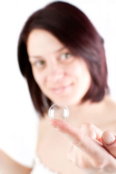 young attractive woman holding soap bubble on her finger