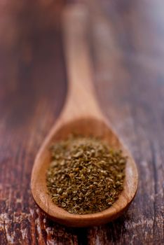 oregano spice in wooden spoon over wood background - selective focus