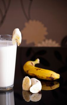 fresh banana smoothie and fruits on black background