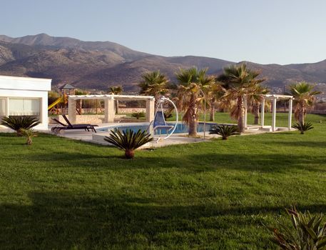 Swimming pool, sunbeds and palms at luxury villa, Crete, Greece