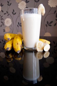 fresh banana smoothie and fruits on black background