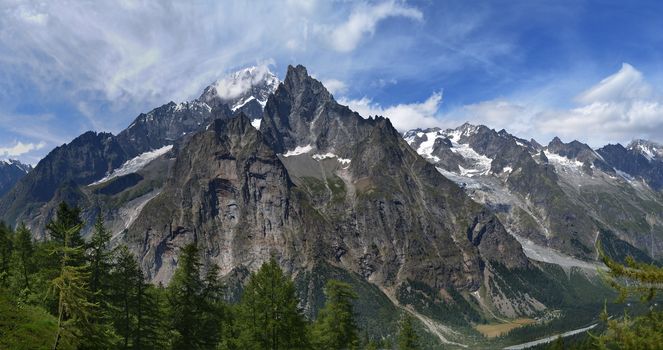 Mountains and pine trees under cloudy blue sky