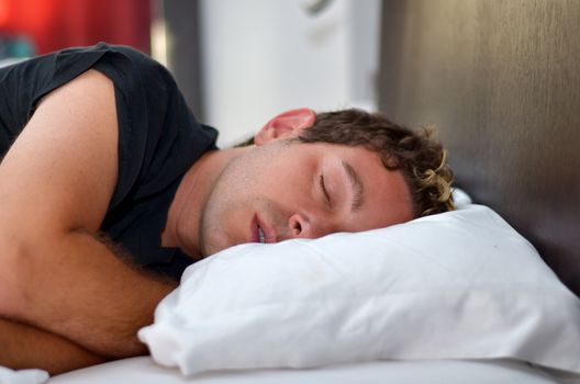 Handsome young man sleeping on white pillow