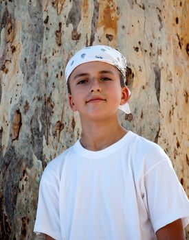 Portrait of a Boy in the bandana on the background of the trunk of eucalyptus.