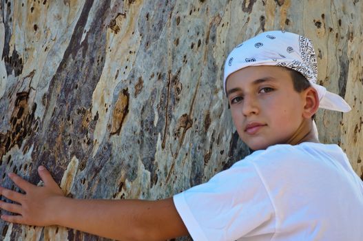 Portrait of a Boy in the bandana on the background of the trunk of eucalyptus.