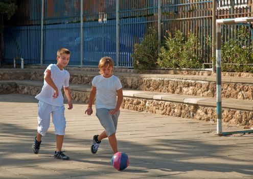 Teenage boys playing soccer at sunny day .