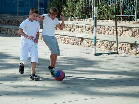 Teenage boys playing soccer at sunny day .