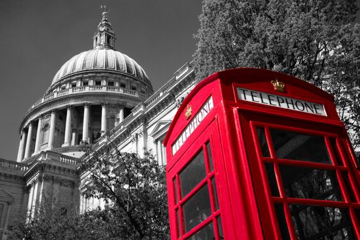 A red London phone box with a black and white St Paul's Cathedral in the background