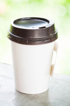 Hot coffee paper cup with green bokeh