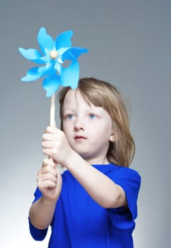 boy with long blond hair in blue top playing with a pinwheel