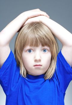 portrait of a boy with long blond hair in blue top - isolated on gray