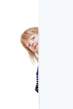 curious boy with long blond hair peeking out from behind a white board looking