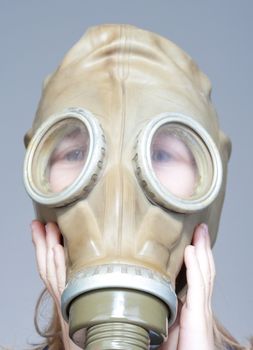 portrait of a boy putting on WW2 gas mask - isolated on gray