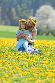 mother and son picking flowers at dandelions field in spring