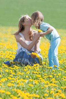mother and son kissing on dandelion field in spring