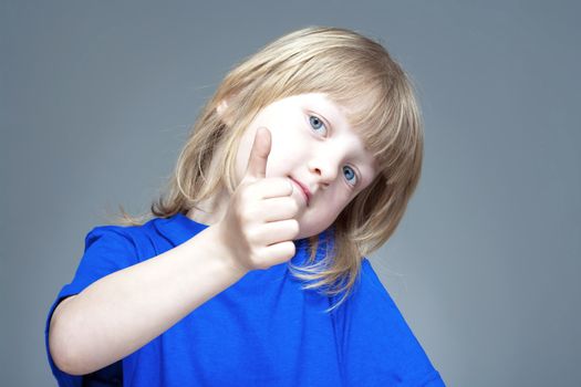 boy with long blond hair showing thumbs up - isolated on gray