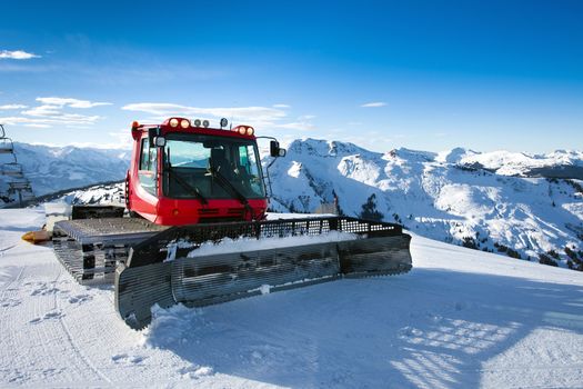 Snow-grooming machine on snow hill ready for skiing slope preparations in Austrian Alps.