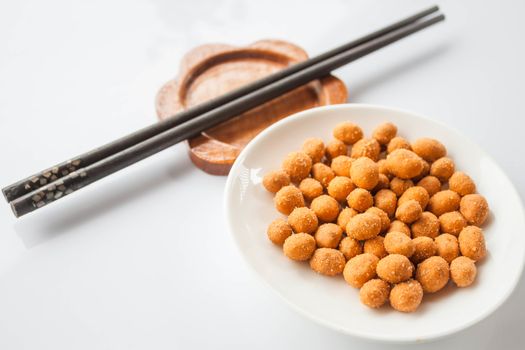 Spicy peanuts snack and chopsticks on white table