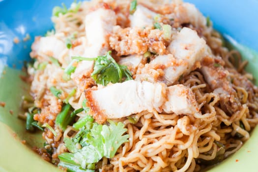 Close up crispy pork on stir fried spicy noodles