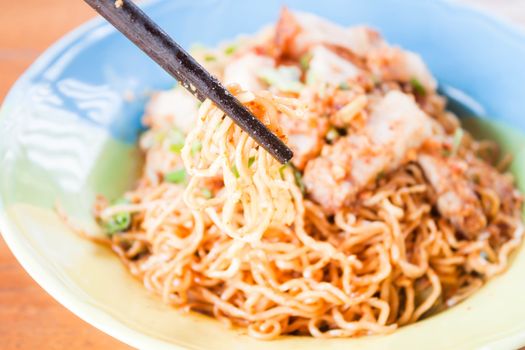 Close up chopstick holding a group of yellow noodles