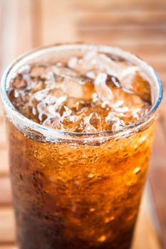 Close up cola drink with ice on wood background