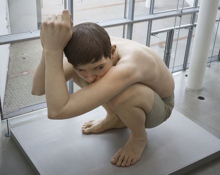 AARHUS, DENMARK - MAY 25: Boy made of the Australian sculptor Ron Mueck exhibited in Aros - The art Museum of Aarhus, Denmark May 25, 2013. Ron Mueck has made fine art since 1996.