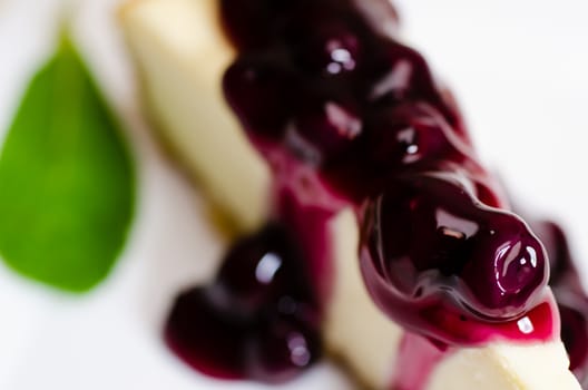 Closeup of slice of blueberry cheesecake  with mint garnish.  Shallow depth of field.